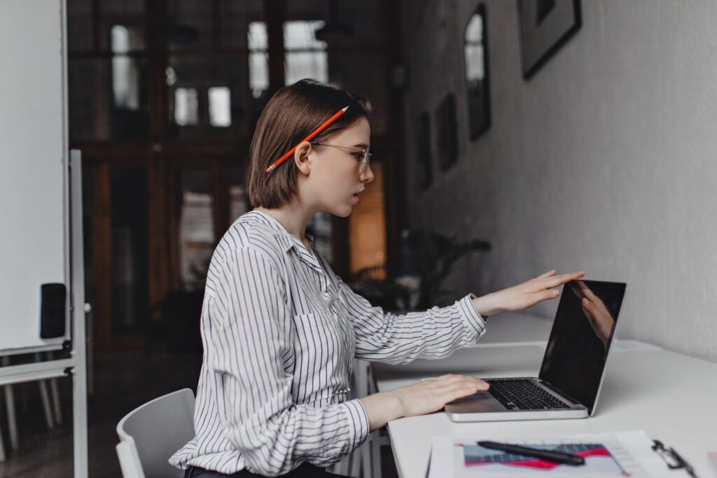 Girl with red pencil behind her ear works in laptop